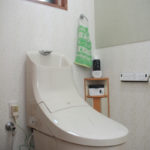 【After】タンク一体型のトイレは、タンクと本体の間の隙間が無いためお手入れが簡単です。壁には品の良いグリーンのエコカラットを採用。空気をきれいにしてくれるだけでなく、壁のデザインのアクセントになっています。