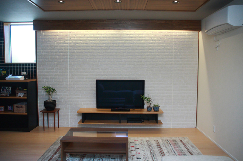 【After】作り付けのテレビ台は、下の空間がフラットなため掃除もしやすく、空間を広く感じさせてくれます。背面の壁は外壁に用いられるタイルを採用し高級感を演出。